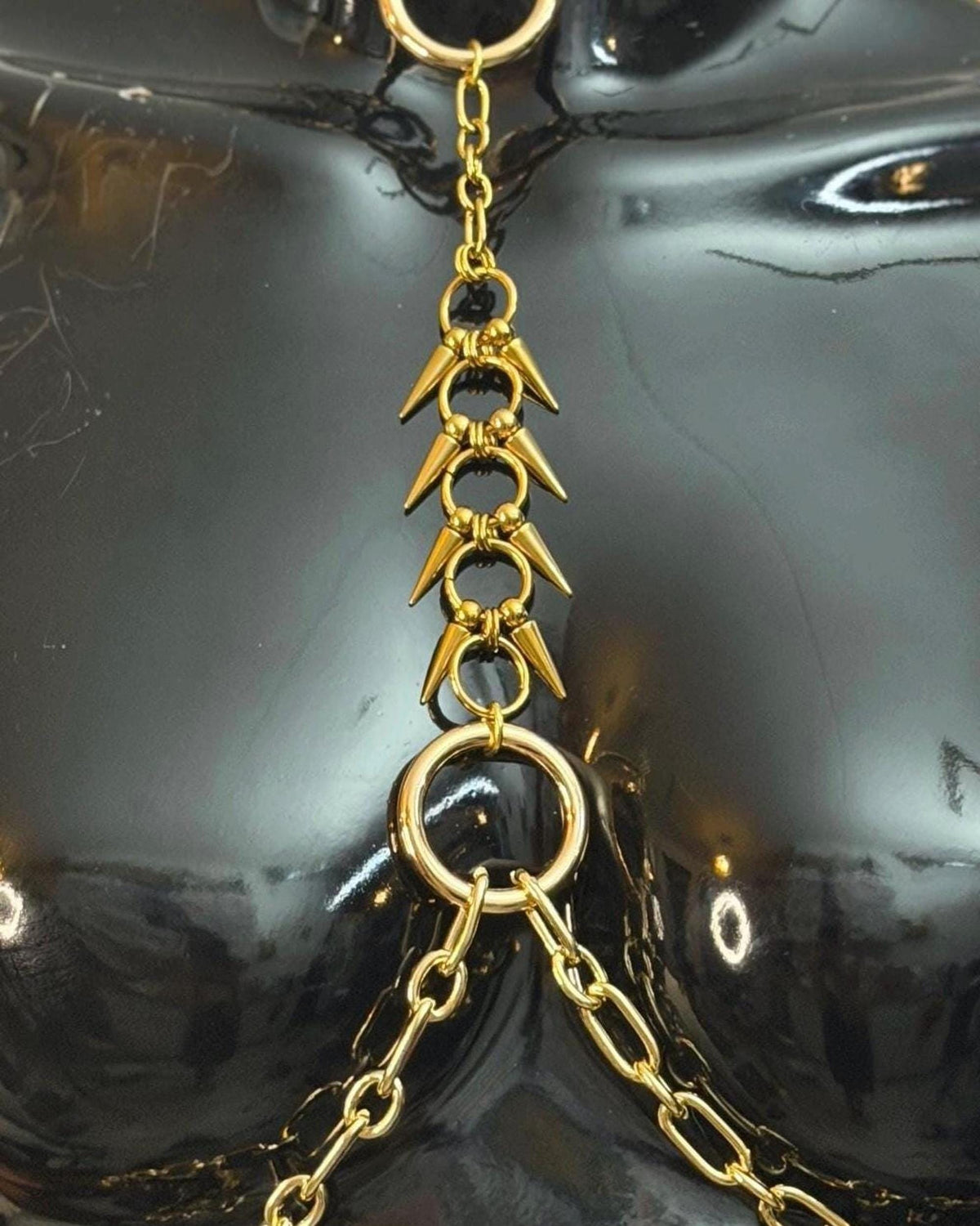 Gold close-up of spike ladder and rings, textured pointed connectors, dramatic gold spine harness detail