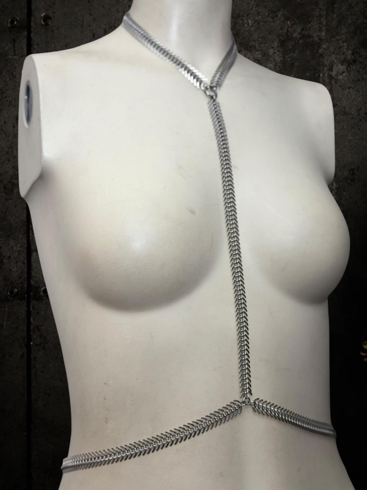 White torso shows spine body chain, Y-shaped stainless steel harness sitting low on waist, festival body jewelry look