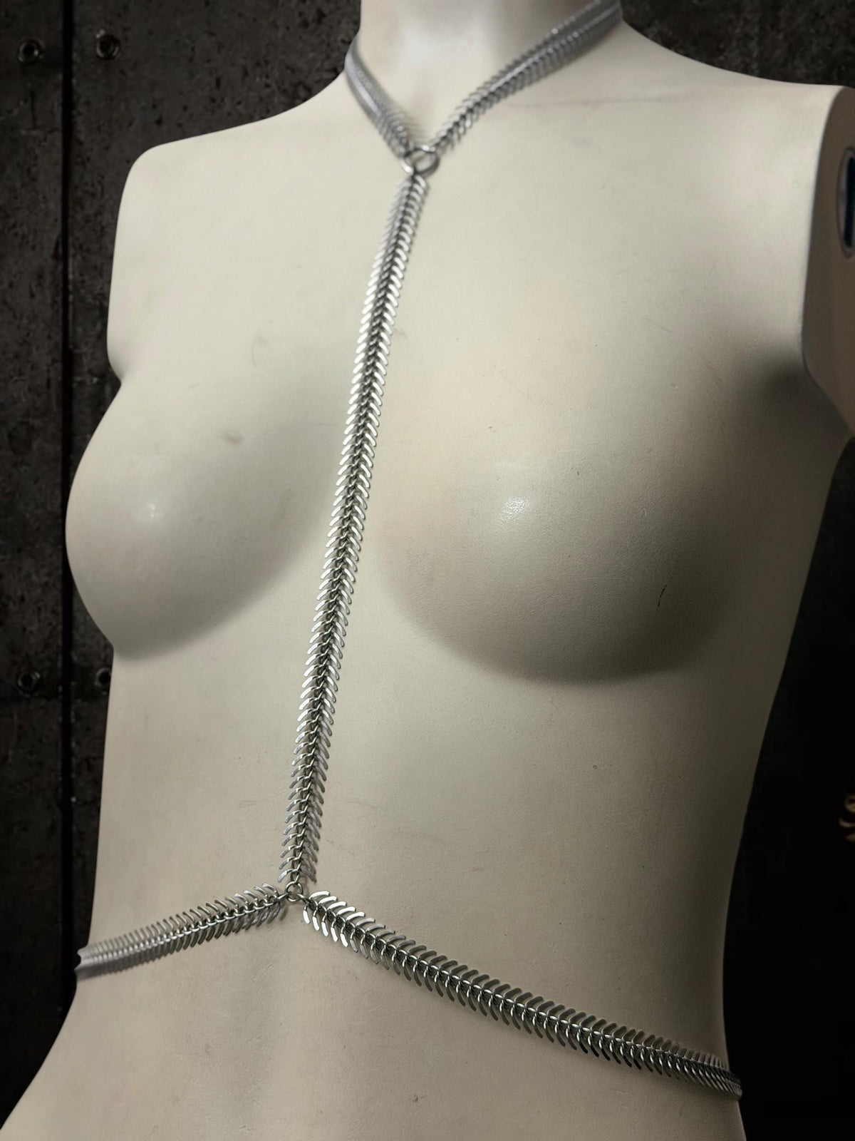 Three-quarter white mannequin wearing spine body chain, adjustable waist connectors, versatile alternative body harness
