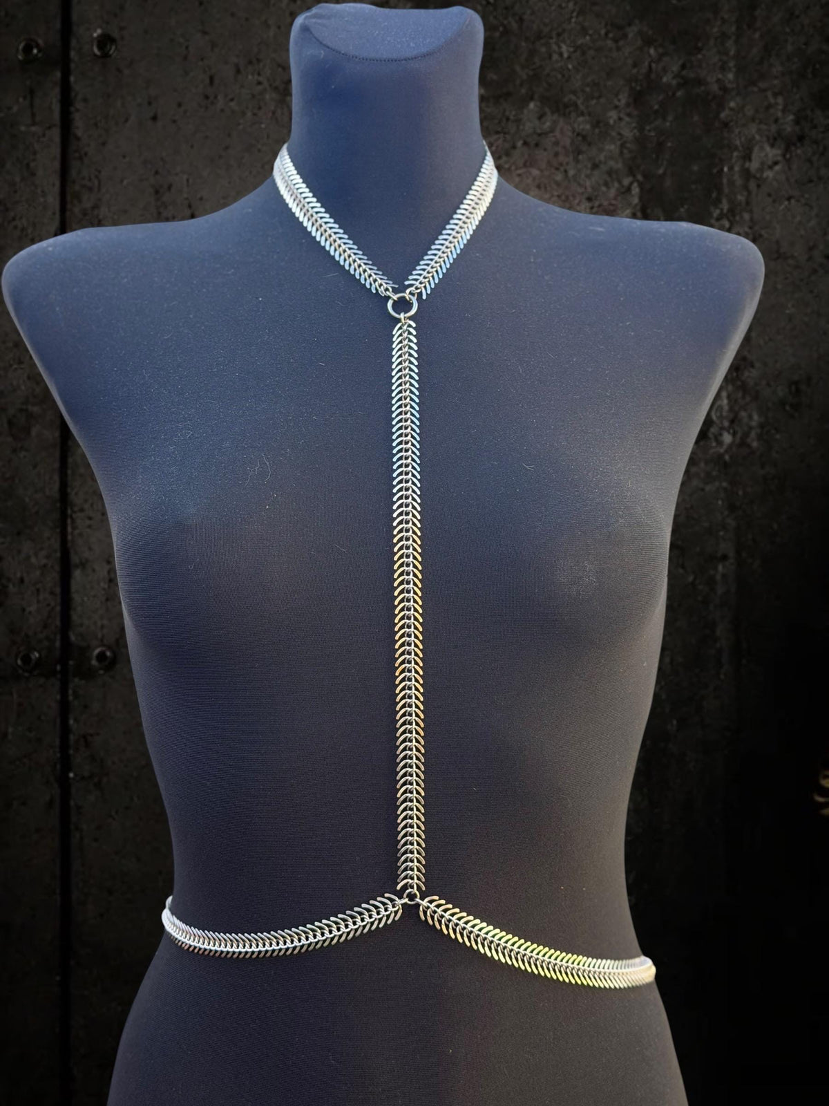 Blue mannequin wearing spine body chain, stainless steel Y silhouette, sleek gothic clubwear accessory