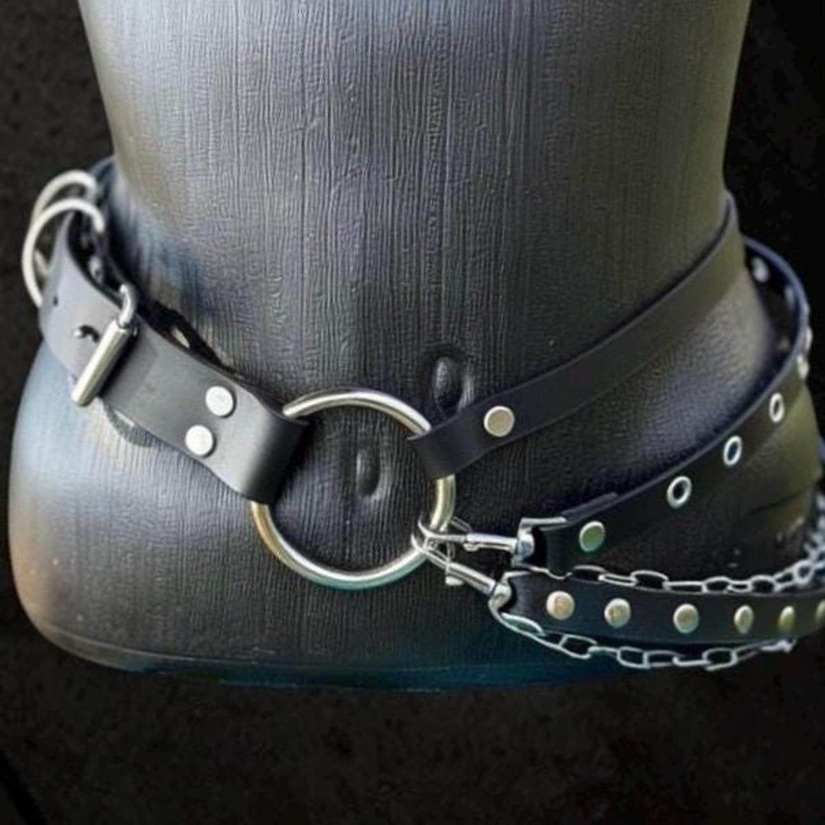 Low angle close-up, O-ring anchored to riveted strap, chunky stainless chains cascade, alternative fashion belt