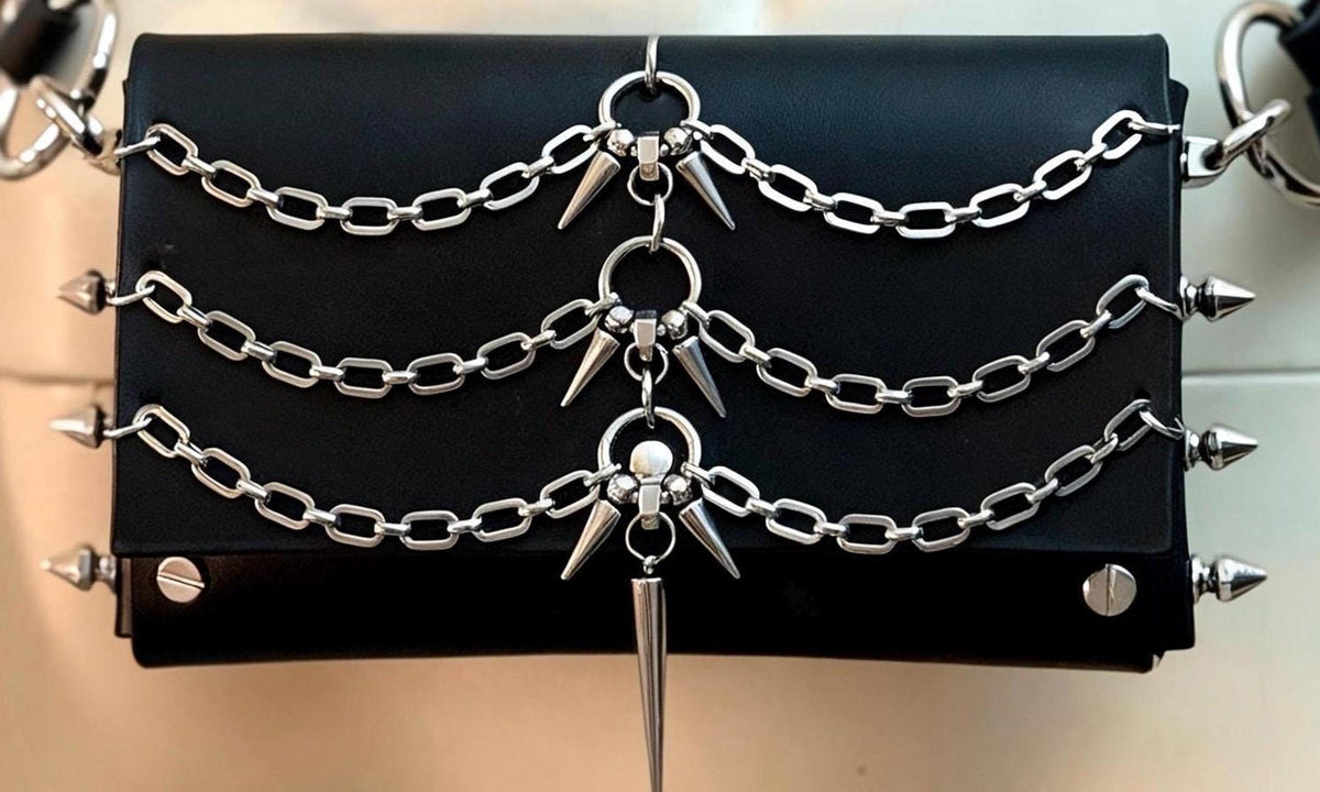 Flat lay front view of spiked leather crossbody bag, three rows of chains, stainless steel spike hardware