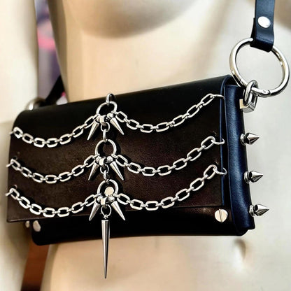Angled close up of O ring and riveted side spike studs, modular belt style punk crossbody bag