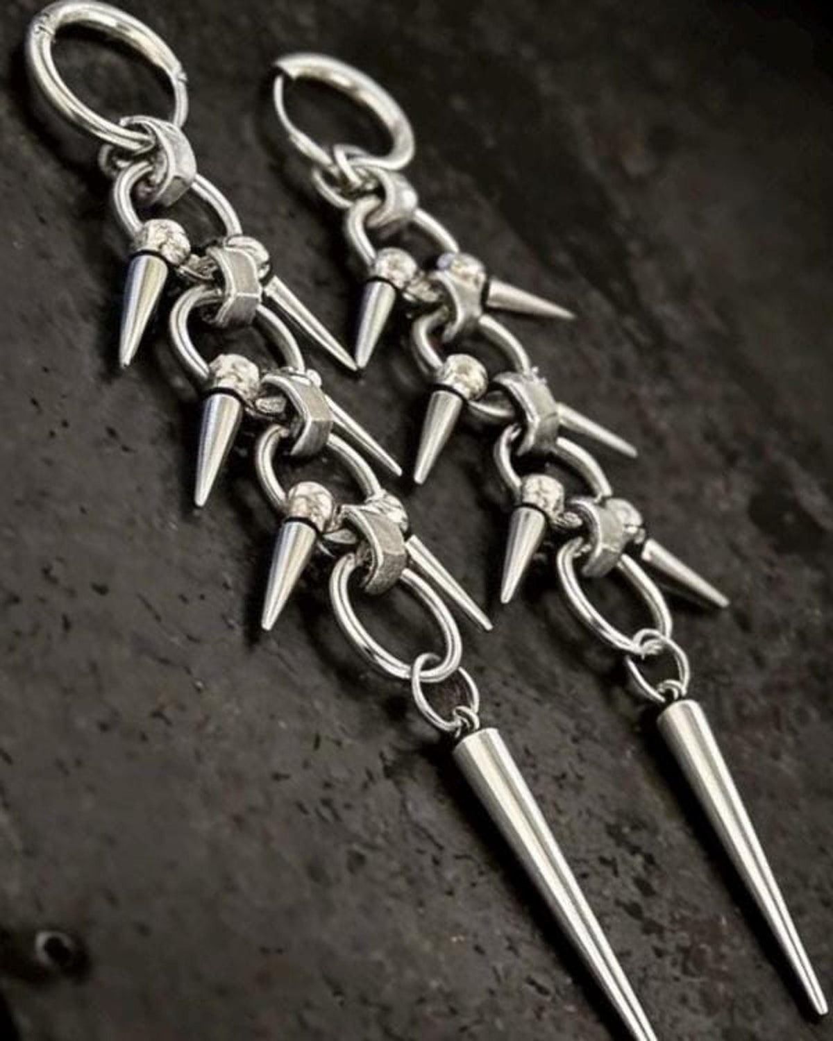 Macro detail of linked chainmail sections and clustered small spike charms on gothic spike dangle earrings