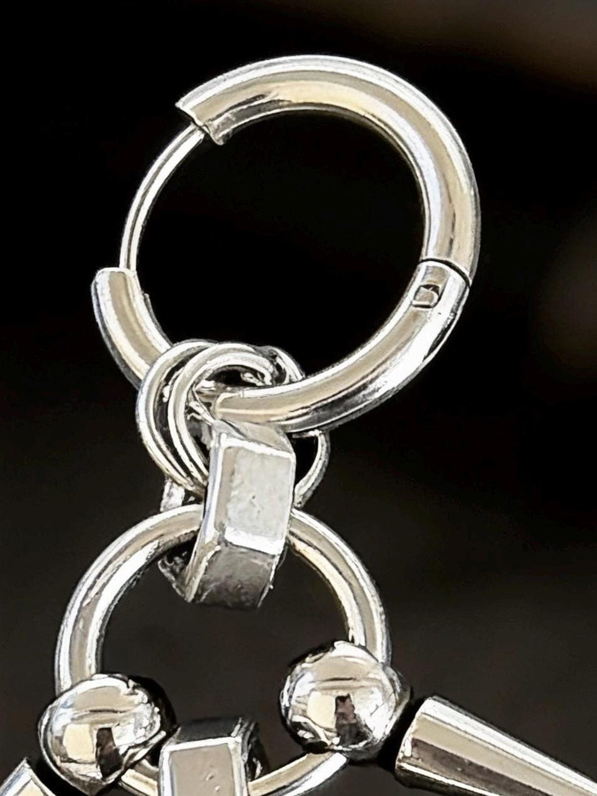 Tight macro of sprung hoop, bead and O-ring connectors, gothic spike dangle earrings hardware in stainless steel