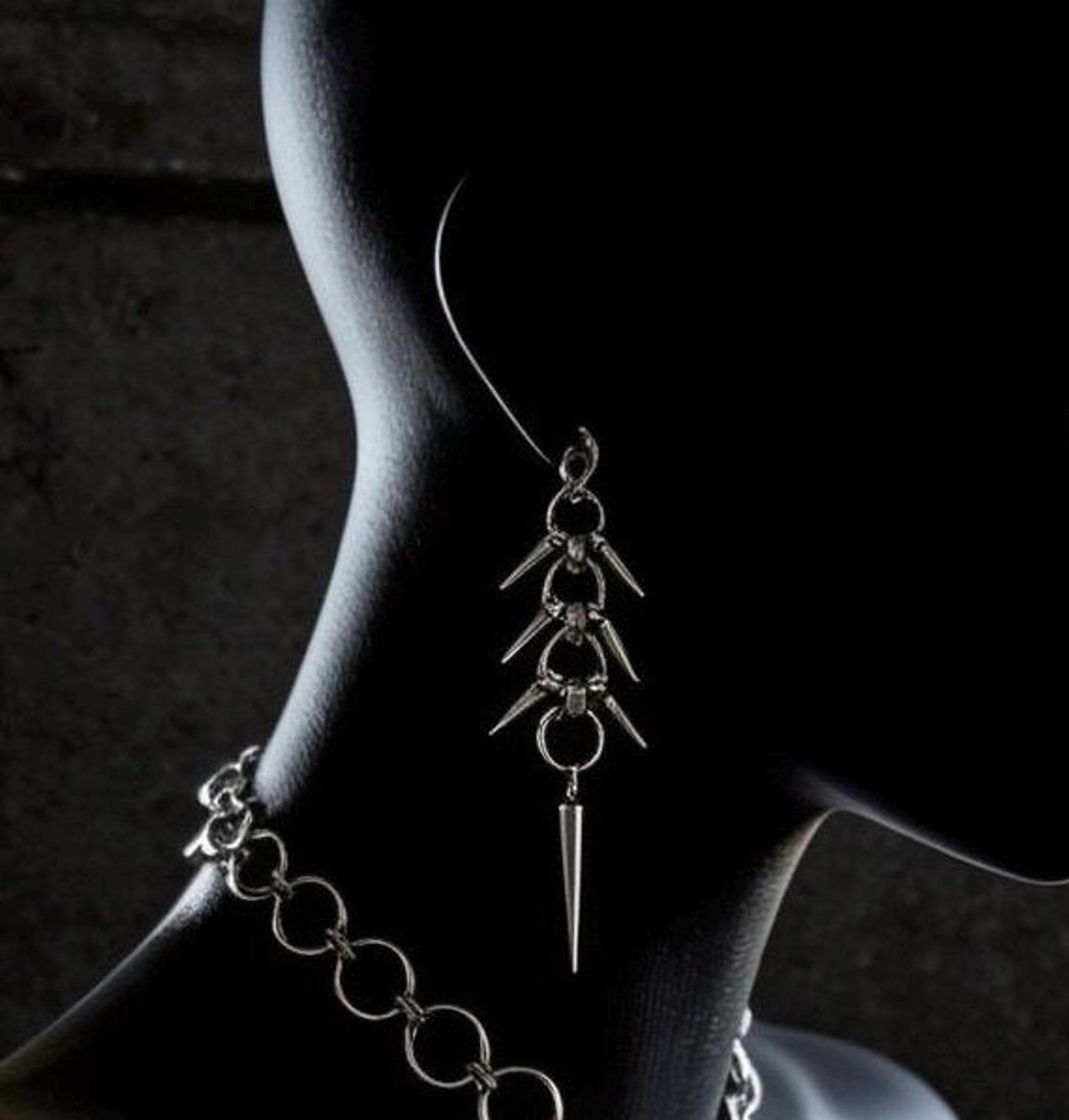 Mannequin profile wearing a dangling spike, alternative statement earrings styled with matching chain collar