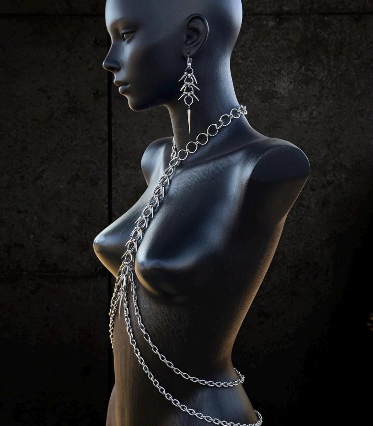 Side profile of black mannequin wearing silver spine harness, neck ring and sculptural vertebrae curve, wearable spine jewelry