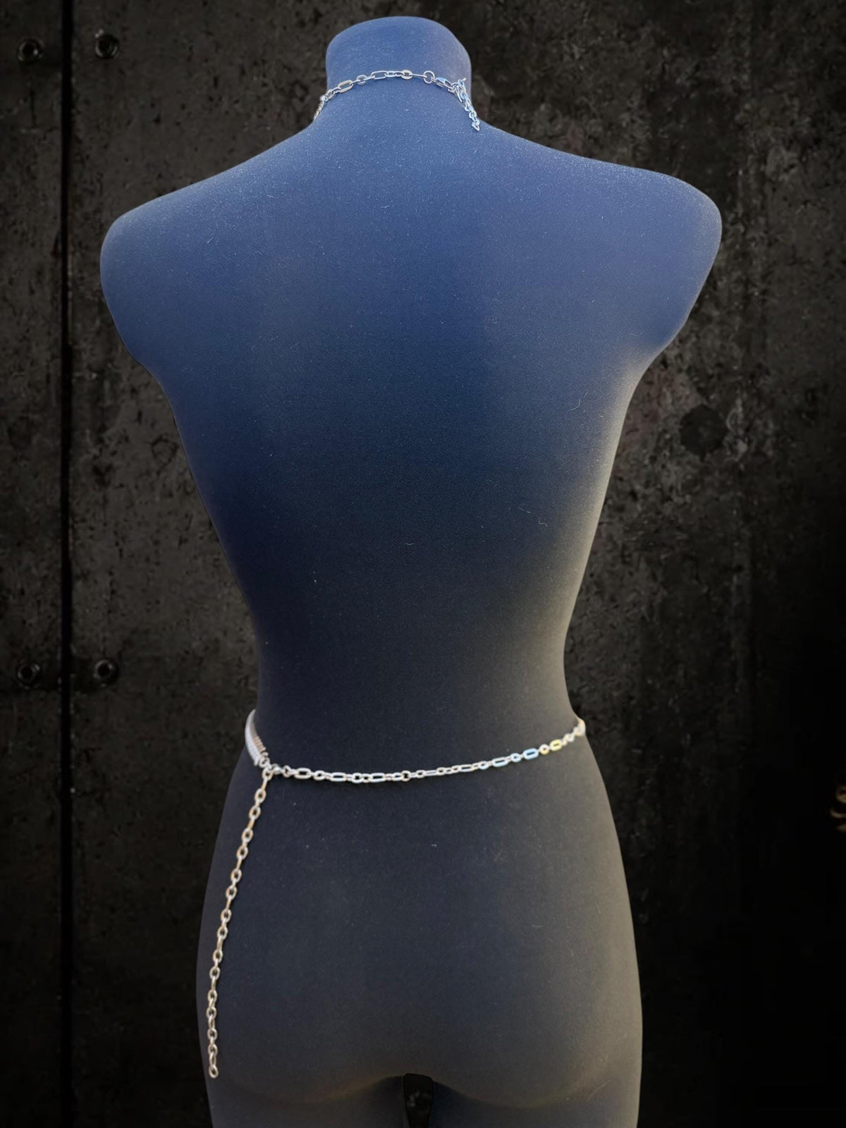 Back view of blue mannequin showing waist loop of spine body chain, subtle neck and waist chain clubwear detail
