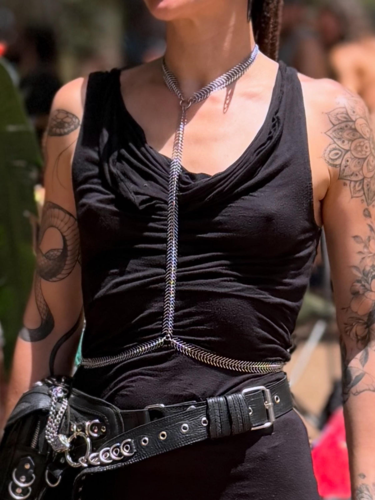 Close-up model wearing spine body chain over black top, rave body chain styled with belt and festival vibe