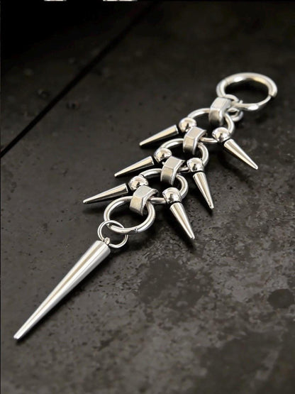 Single earring angled on black surface, chainmail spike earrings with stacked spikes and articulated links